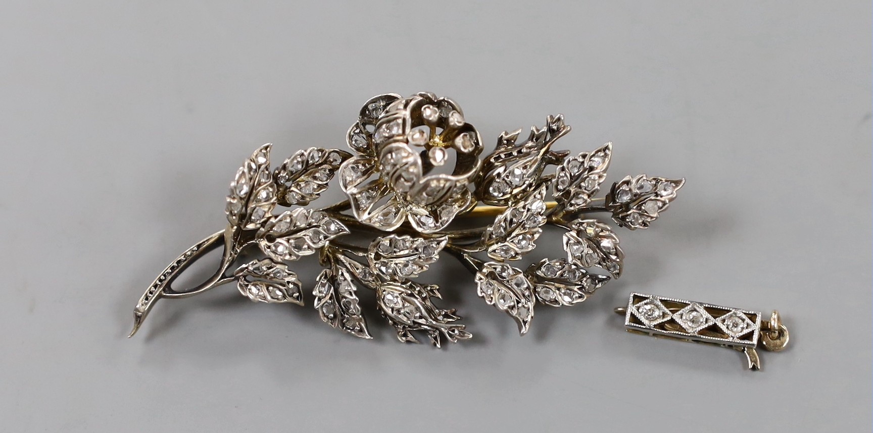 A late 19th/early 20th century yellow metal diamond chip set set floral spray brooch, 52mm, gross weight 10.8 gram and a diamond set clasp.
